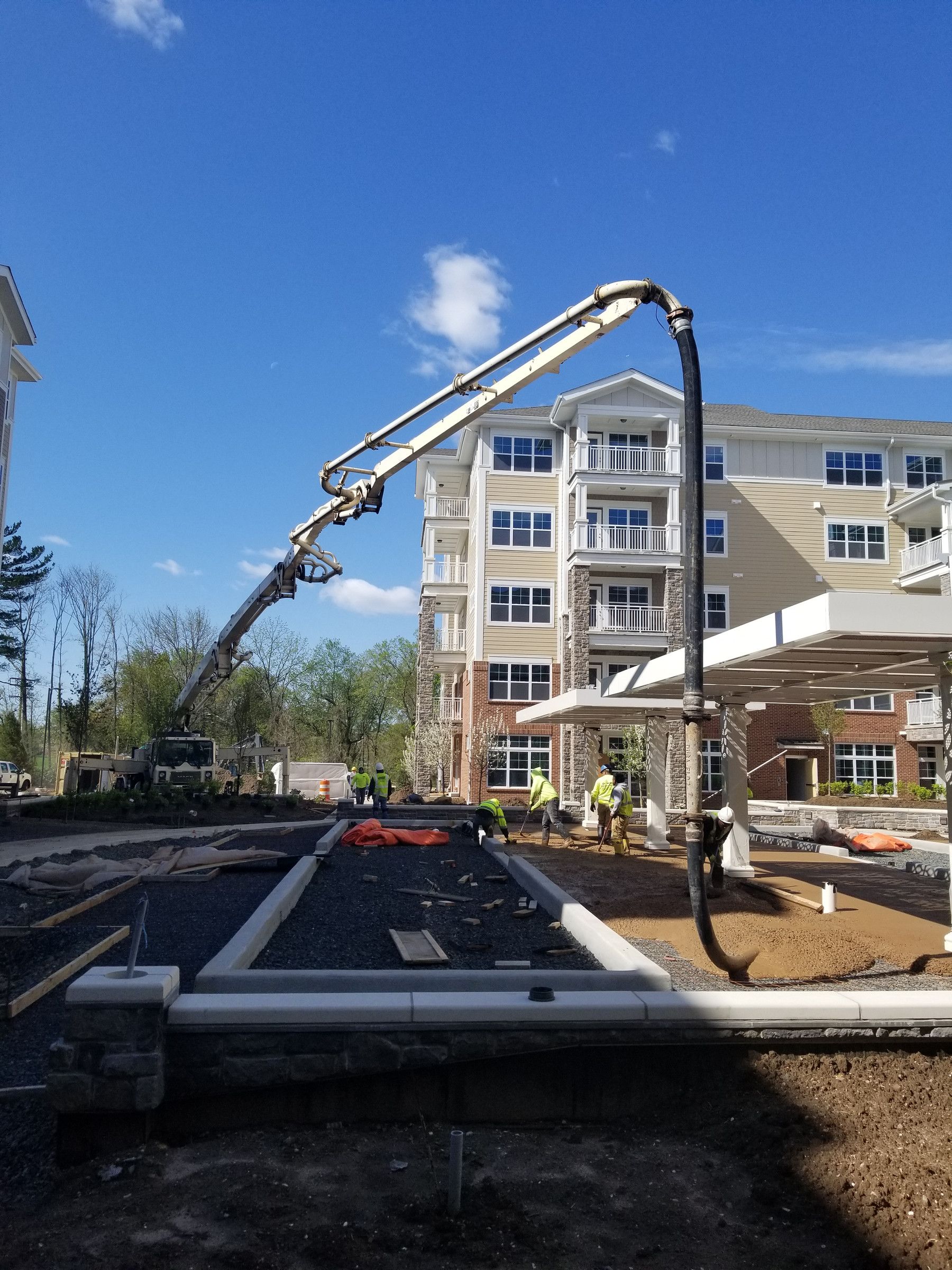 A&S boom pump placing concrete for a crew beside a new apartment building
