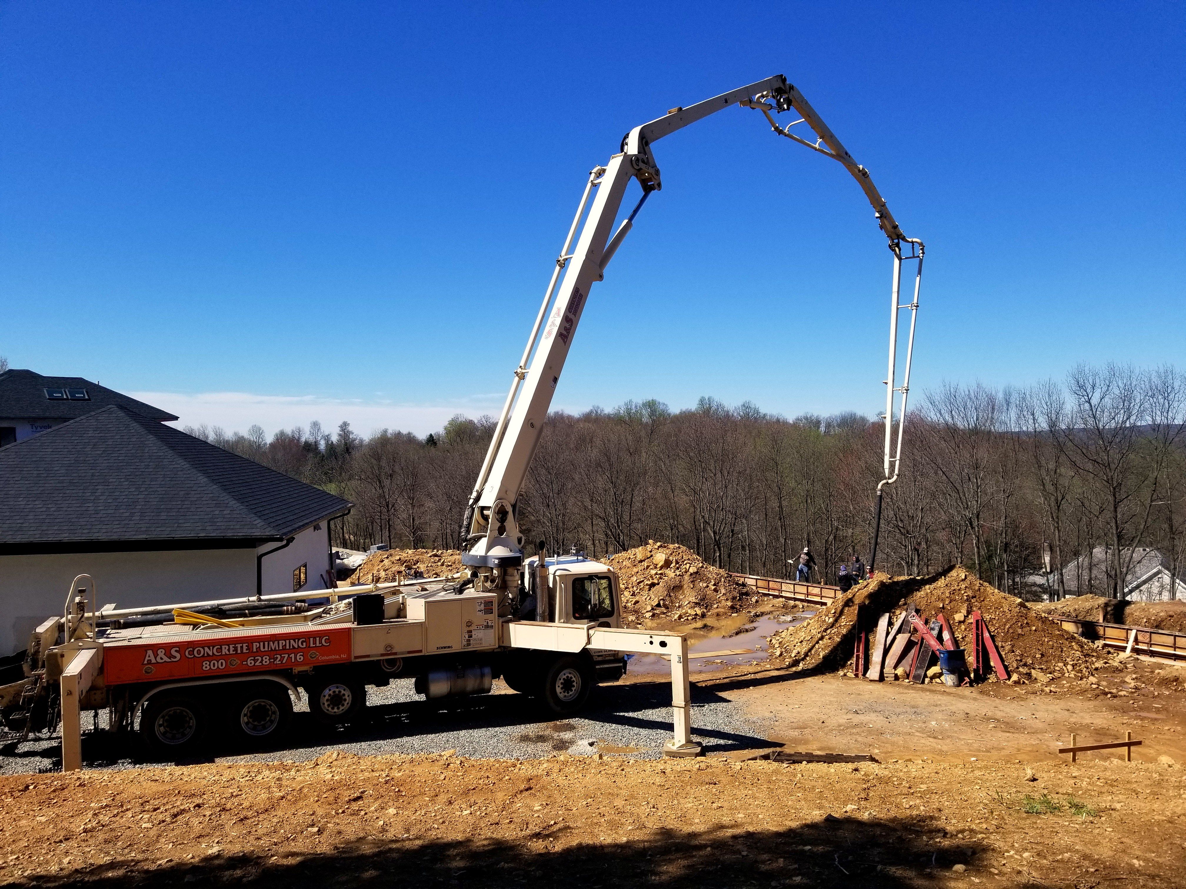 Boom pump placing concrete beside a new home