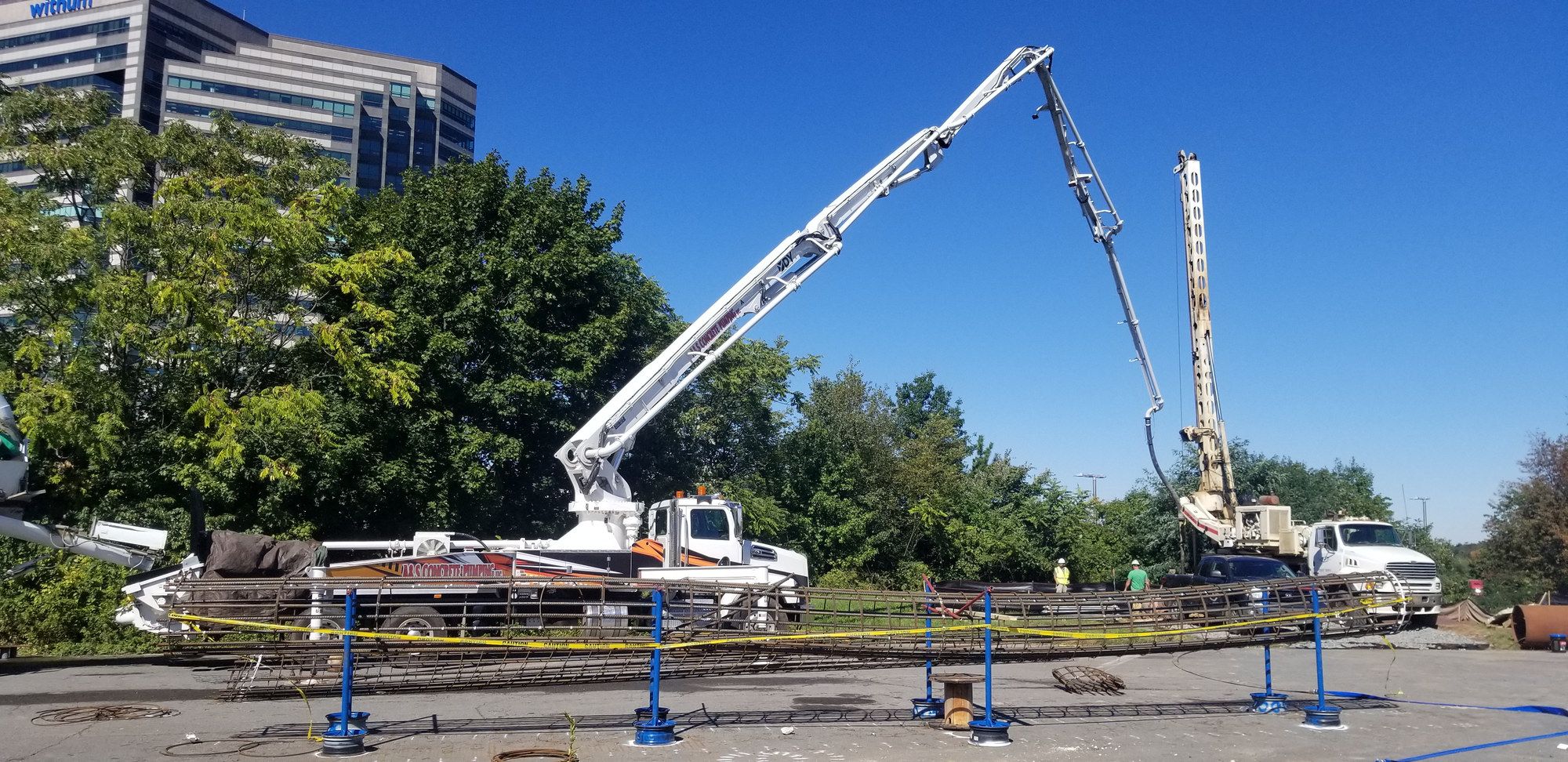 Two boom pumps set up on their outriggers at a job site