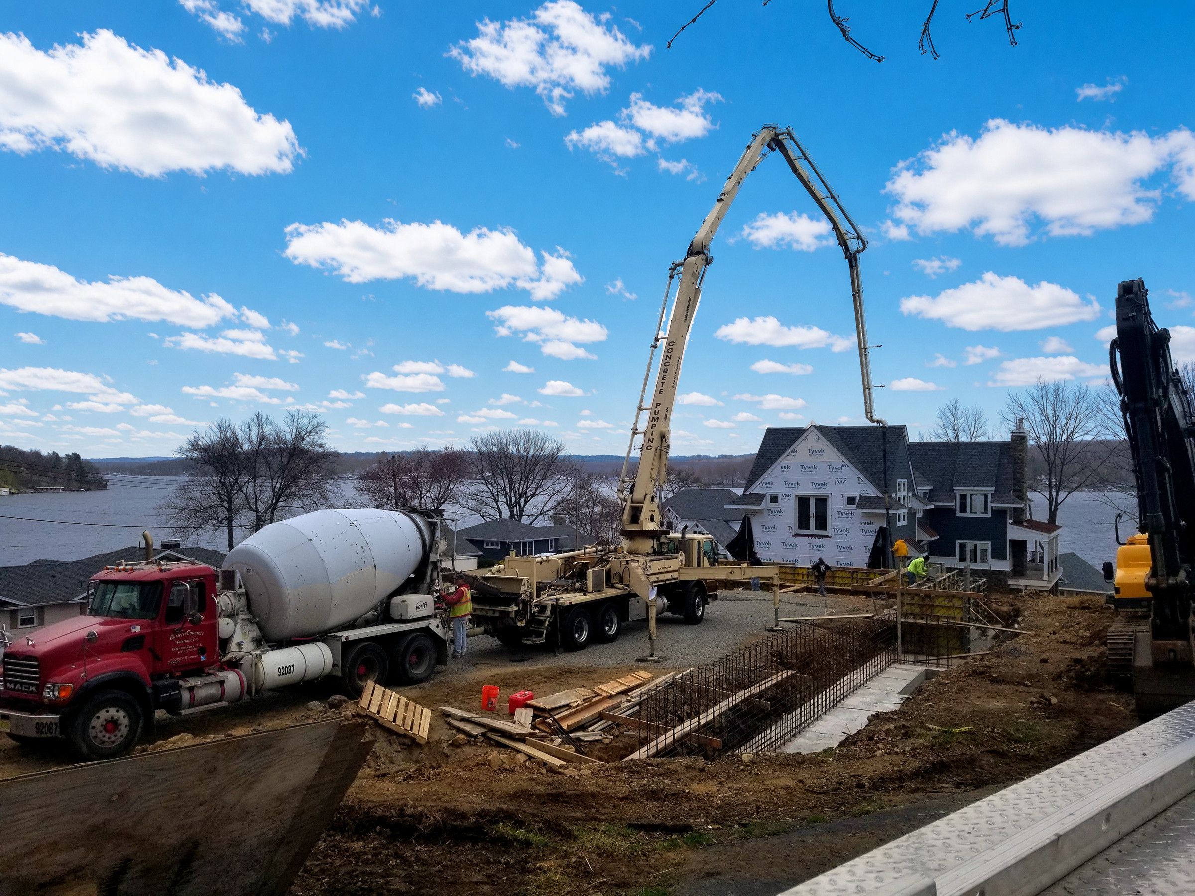 Ready-mix truck feeding a concrete boom pump at a new home foundation