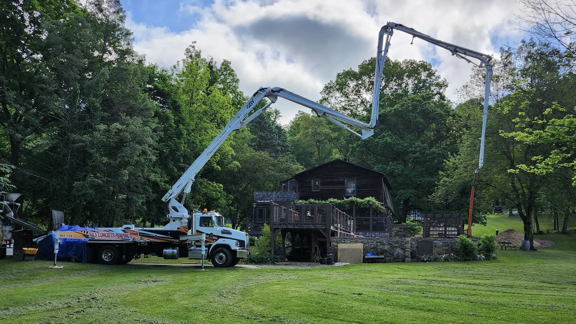 A&S boom pump reaching over a lawn to a pour beside a house