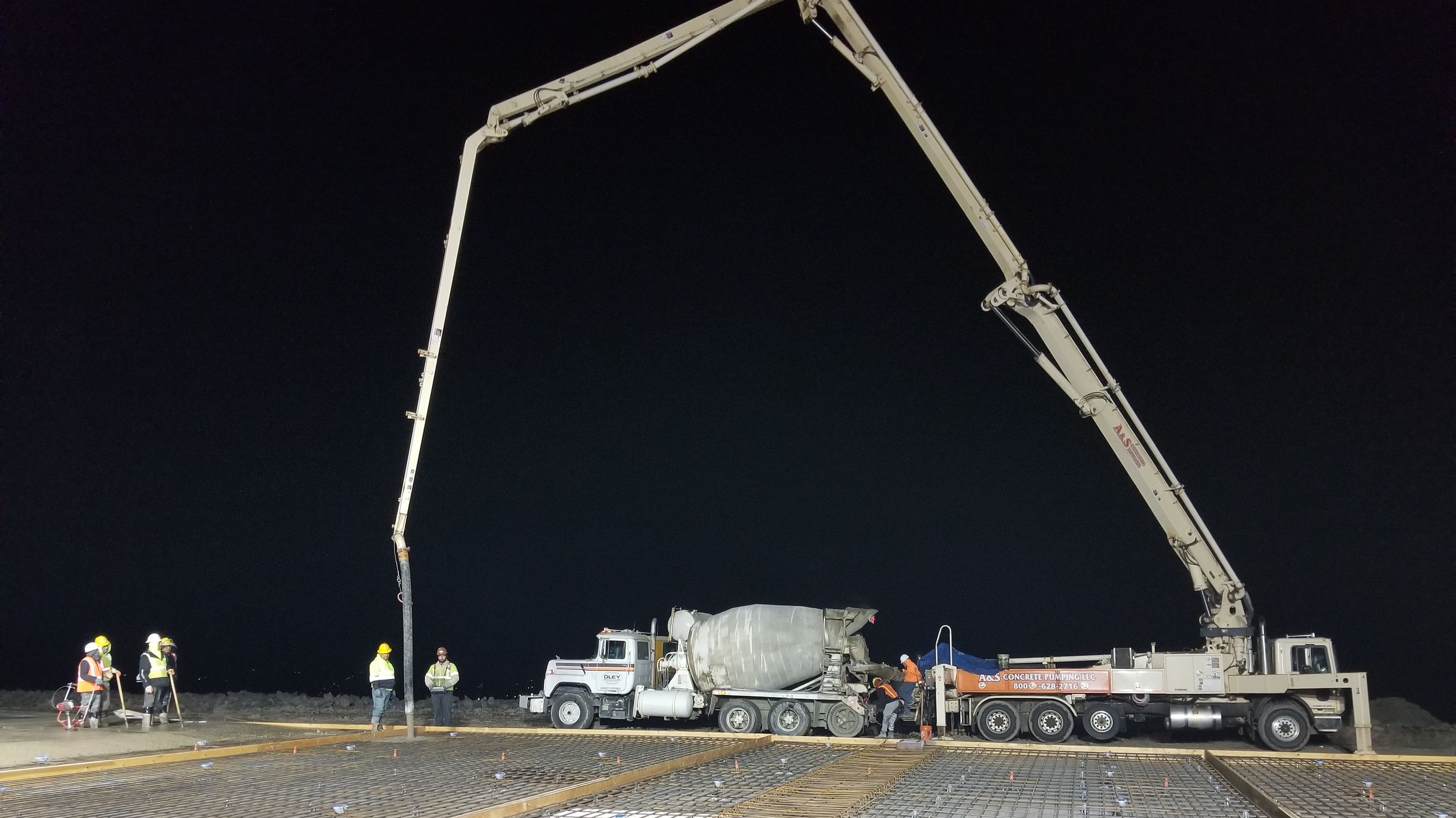Boom pump placing a large slab at night under work lights