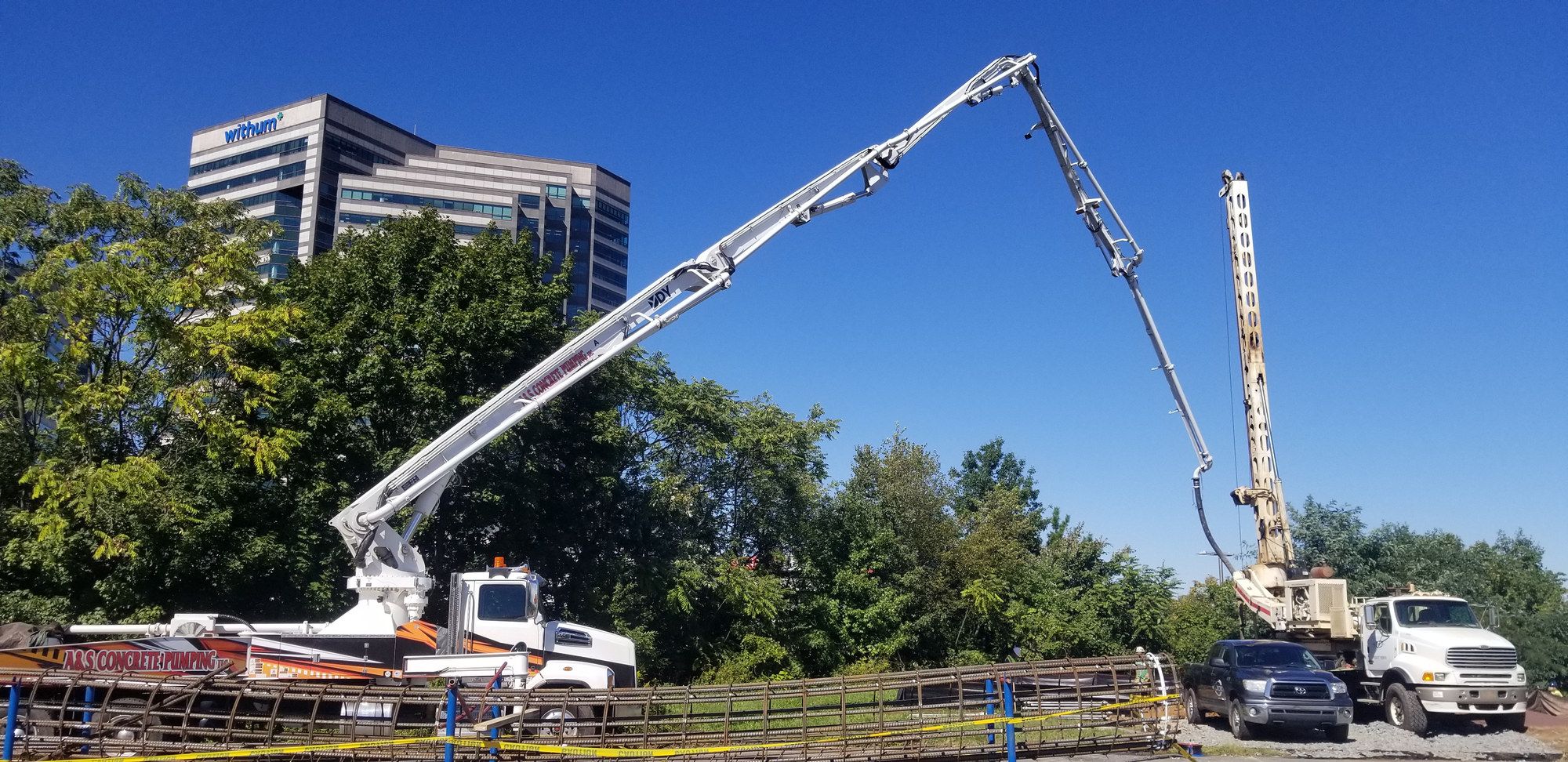 Two A&S boom pumps set up side by side on a commercial site
