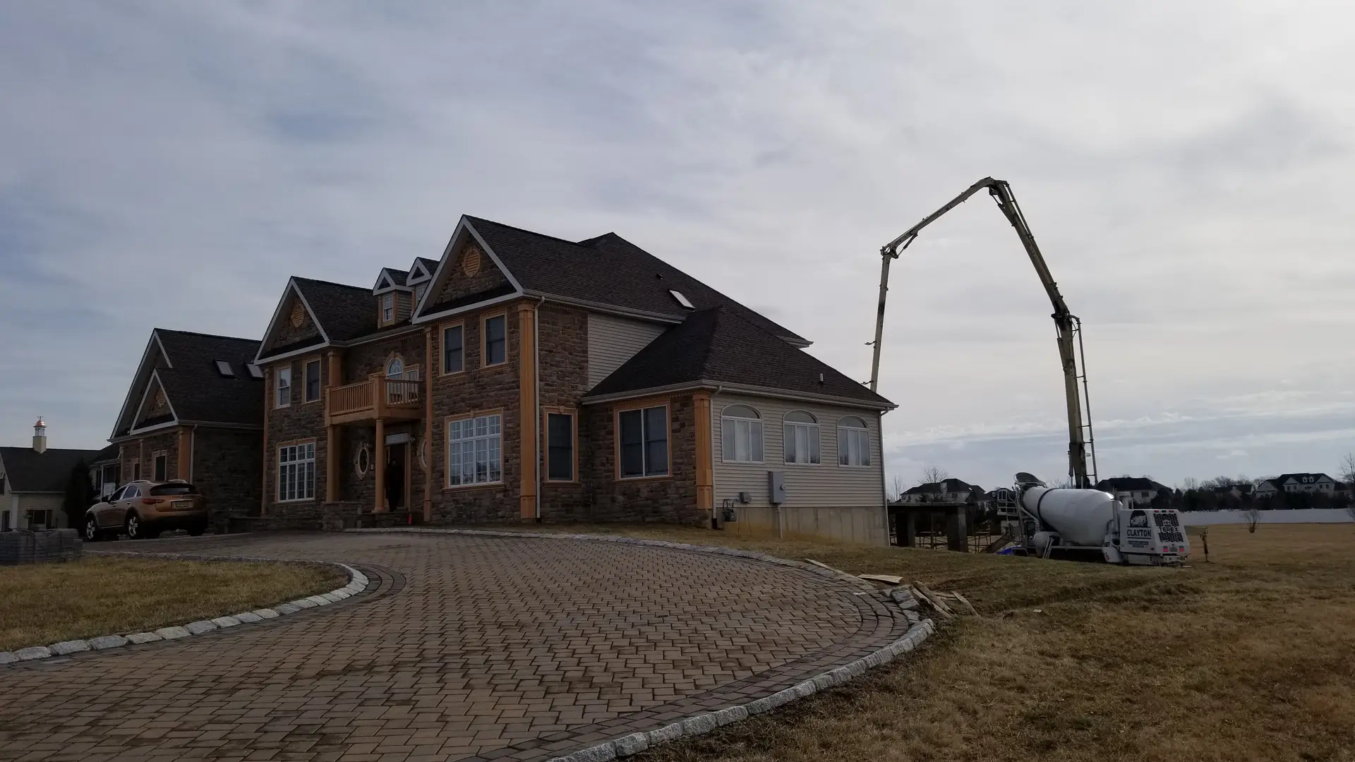 Boom pump set up beside a large new home, ready-mix truck at the pump
